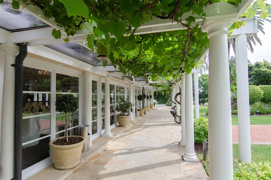 The Enchanted Garden colonnade at Oatlands Estate, vine-shaded with potted topiary