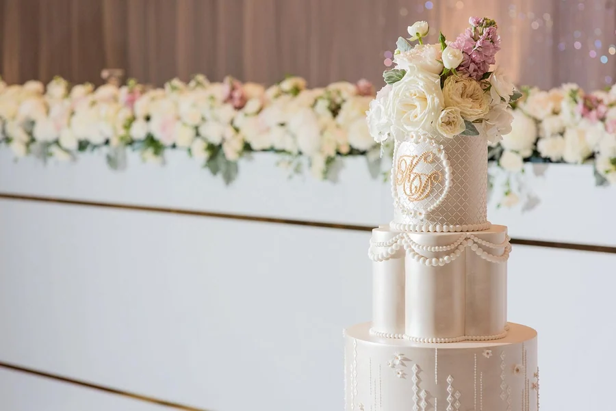 Celebrating In Style &mdash; a white floral wall behind the wedding cake
