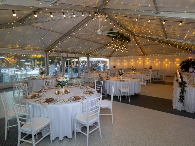 In The Grove — marquee reception with round tables and floral décor