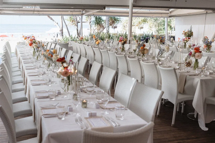 The patio at Sails Noosa, long tables set with views over Noosa Main Beach