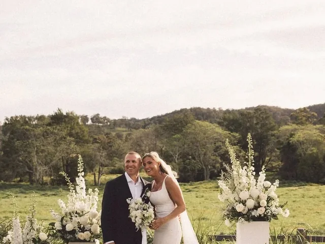 A bride and groom between tall floral arrangements on the lawn at Wallaringa Farm