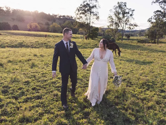 A bride and groom walk hand in hand across the paddock at Wallaringa Farm