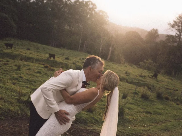 A groom dips his bride for a kiss at sunset on the paddocks at Wallaringa Farm