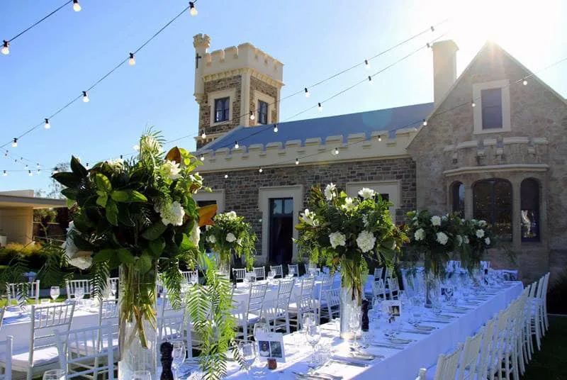 Glanville Hall &mdash; a long table under the fig, festoon lights and hanging florals