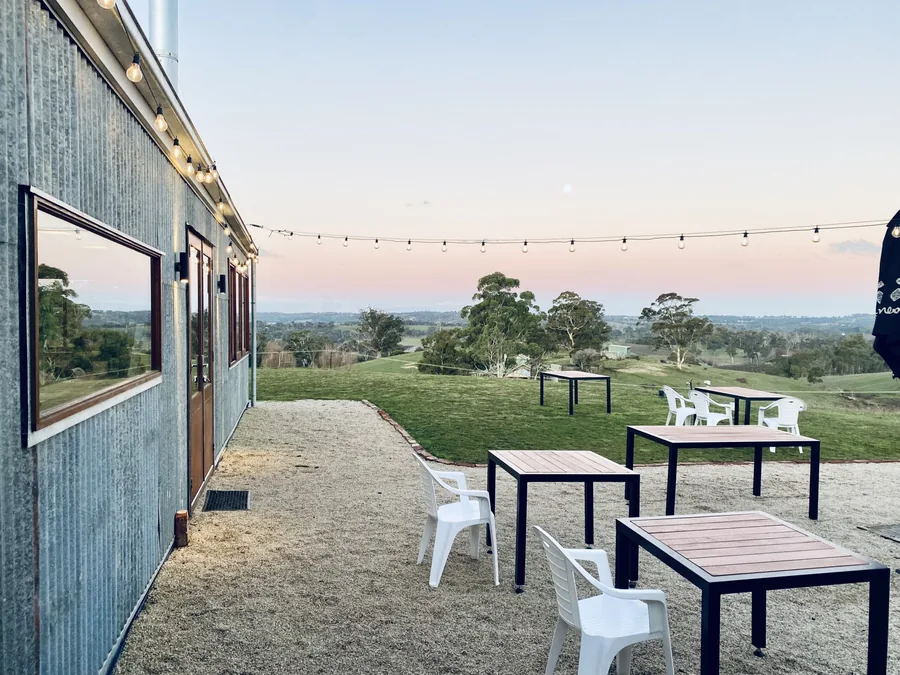 Tilbrook Estate &mdash; the outdoor terrace at dusk, festoon lights over the valley