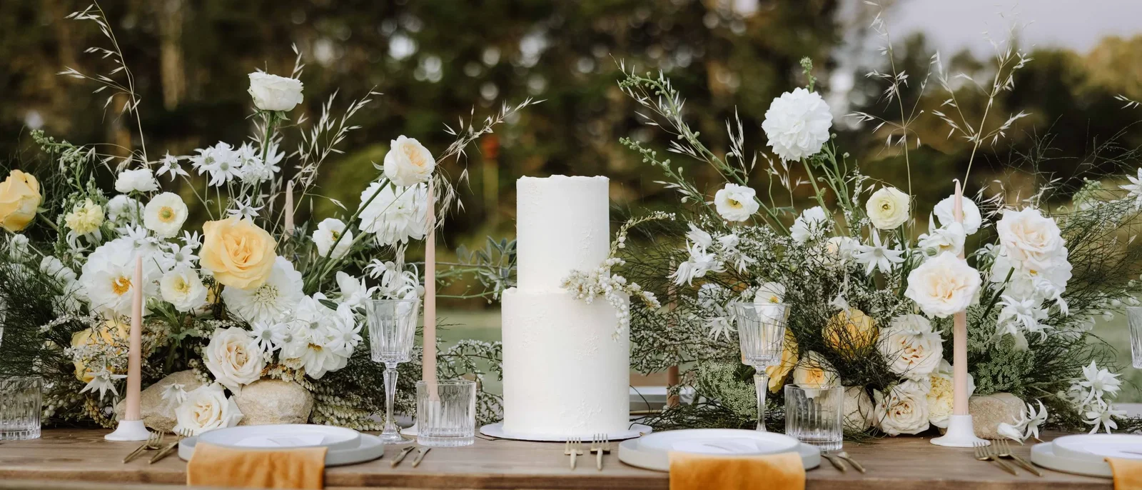 Two-tier white wedding cake on a styled table with flowers