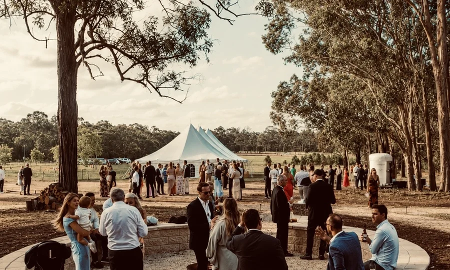 Wedding guests gathered on the open grounds at Adeline Estate, with the marquee and bushland beyond