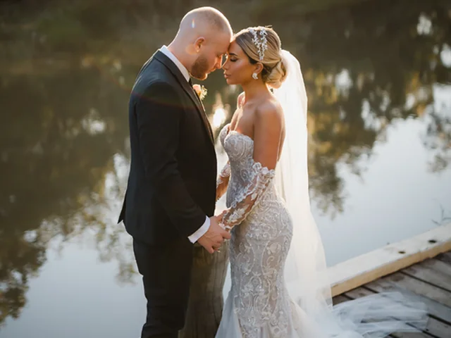 ATEIA Photography & Video: Newlyweds kiss on a jetty beside the water at golden hour