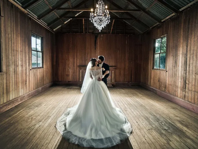 LM Images: Couple kissing beneath a crystal chandelier in an old timber hall