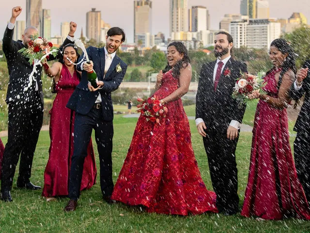 LM Images: Bridal party in red gowns throwing petals with the Brisbane skyline behind