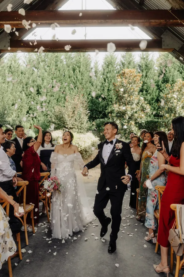 Fable Weddings: Bride and groom walking back down the aisle under falling petals