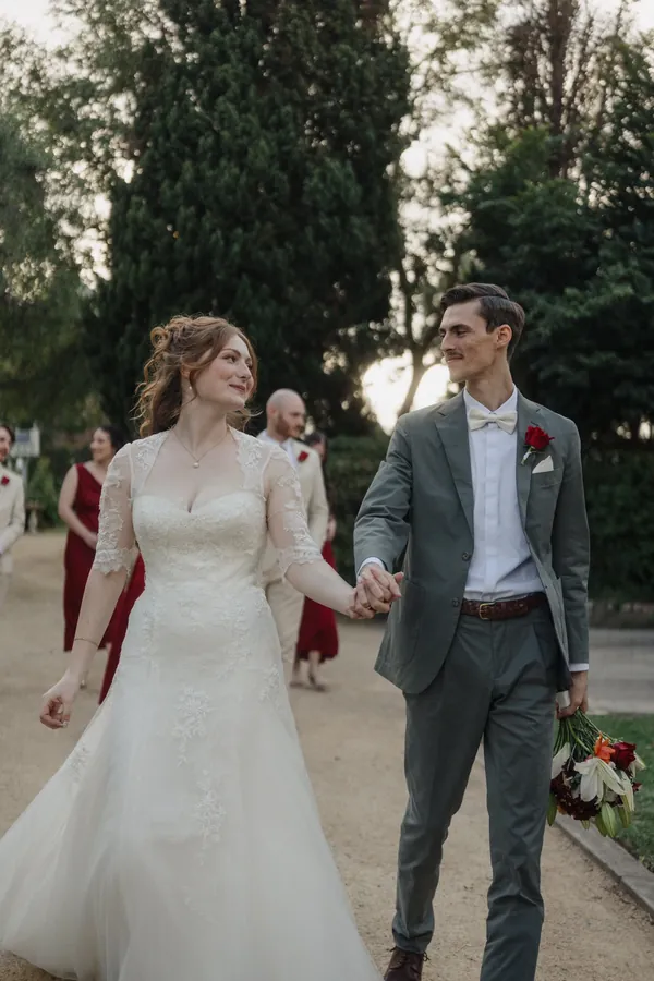 Fable Weddings: Bride and groom walking hand in hand through a garden