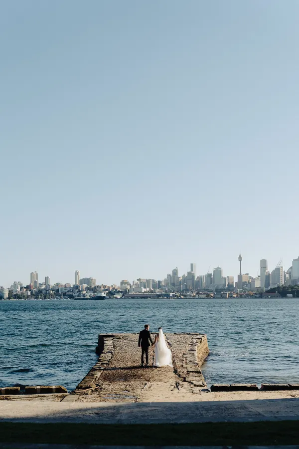 Fable Weddings: Couple on a harbour jetty with the Sydney skyline behind