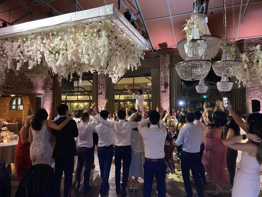 Wedding DJ Hire: guests in a circle on the dance floor under floral chandeliers