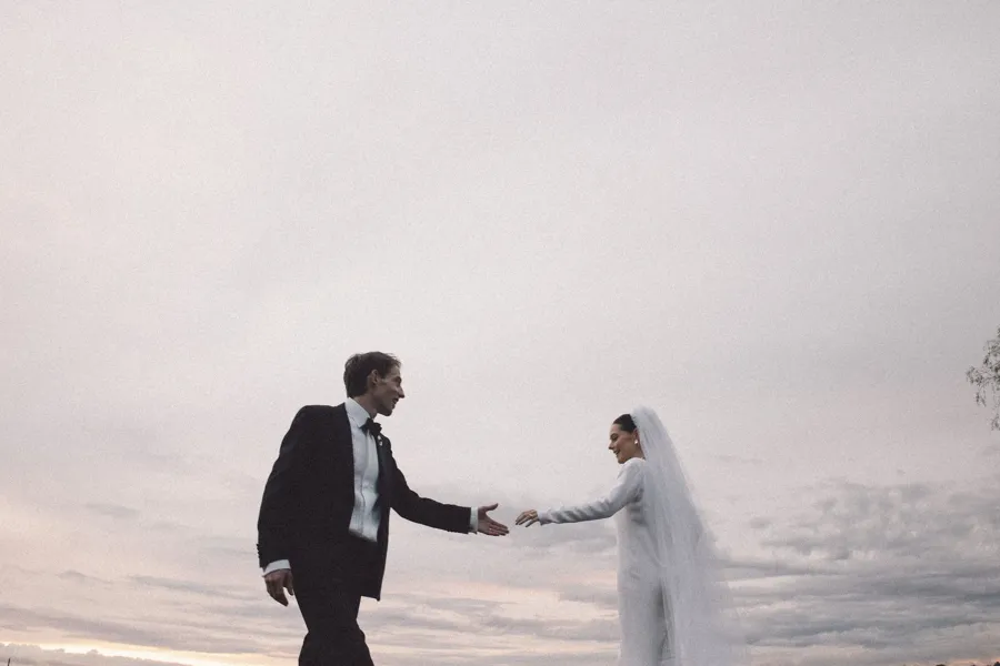 Rogue Weddings: the couple reaching for each other against a pale sky