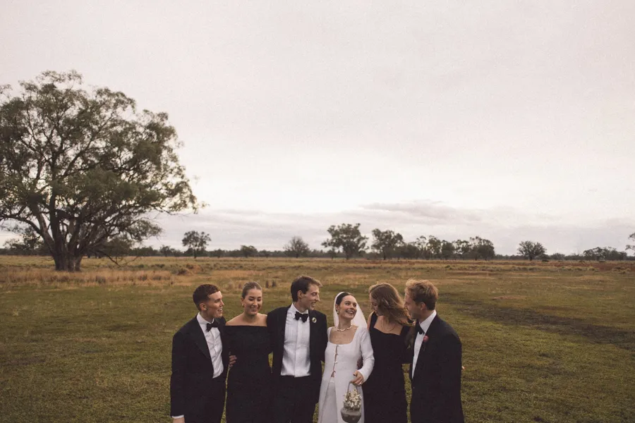 Rogue Weddings: the bridal party under a wide sky beside an old tree