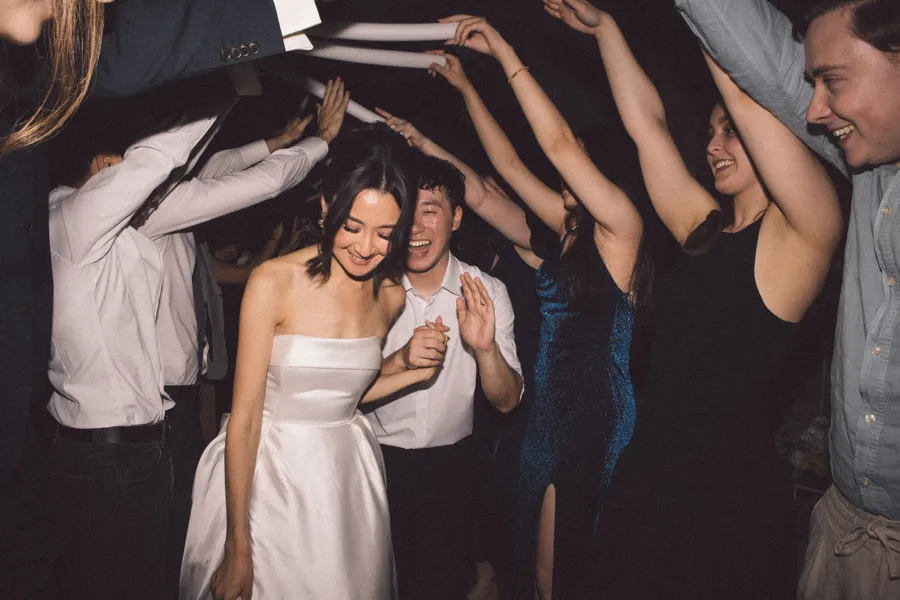 Rogue Weddings: the couple running through a guest arch on the dance floor