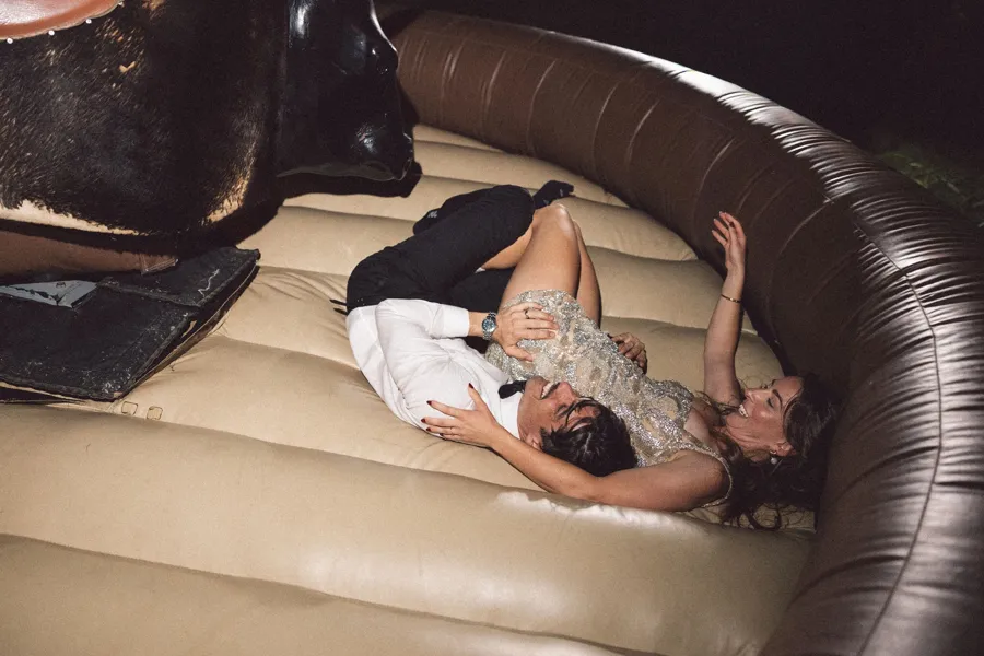 Rogue Weddings: the couple laughing on a mechanical bull mat