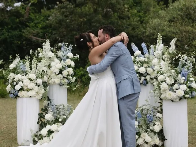Lovesick Weddings: Couple kiss in front of white floral plinths at a garden ceremony