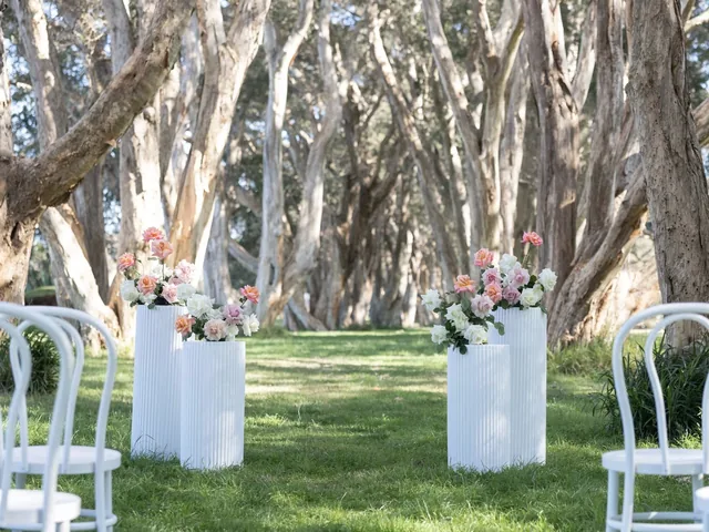 Lovesick Weddings: White chairs, plinths and florals set among paperbark trees
