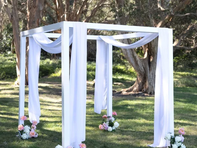 Lovesick Weddings: White four-post arch draped in chiffon with florals