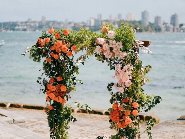 Lovesick Weddings: Floral arch on the sand with the Sydney skyline behind