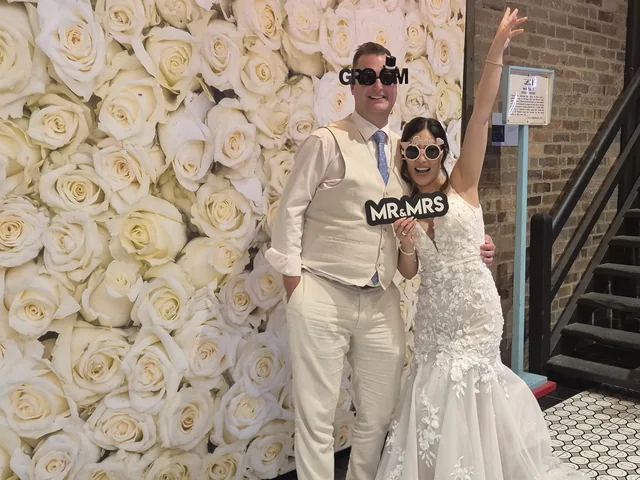 Sydney DJ & MC Services: Bride and groom with Mr & Mrs props at the photo booth rose wall