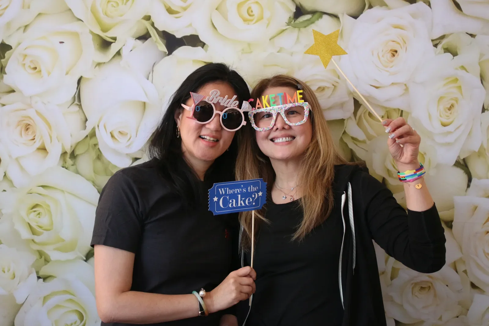 Two guests in Bride and Cake Time glasses holding a Where is the Cake sign at the photo booth