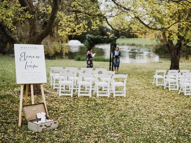 White ceremony chairs set out on the lawn by the lake