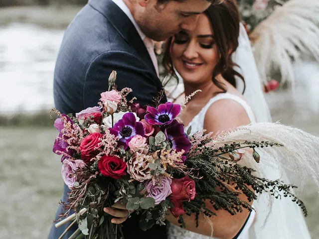 Newlyweds embracing with a bold bridal bouquet