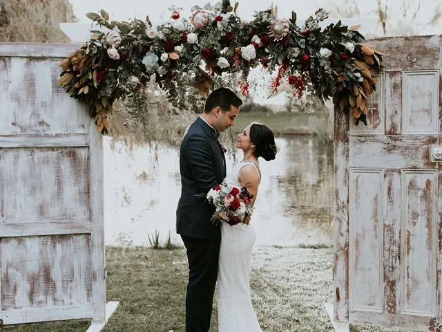 Couple beneath a rustic floral ceremony arch